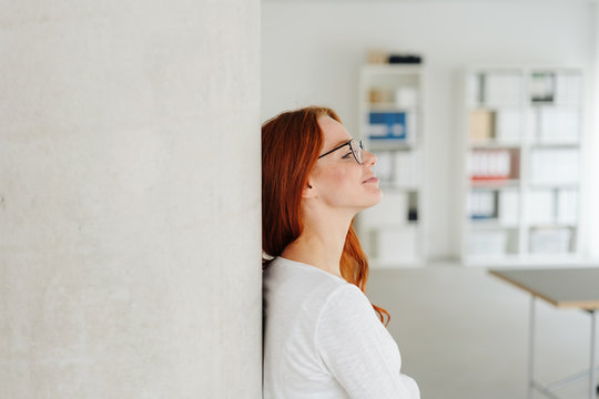 Young woman standing daydreaming in the office