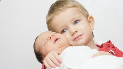 Blue eyes little child hold newborn baby brother, portrait of true family love