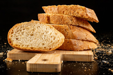 Pieces of fresh baguette on a wooden board. Delicious bread prepared to make sandwiches.