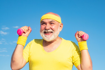 Senior male is enjoying sporty lifestyle. Happy Senior man exercising with lifting dumbbell outdoor. Elderly man after her workout.