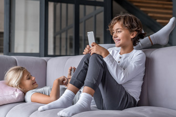 Sister and brother surfing net and playing on smartphone and digital tablet at home