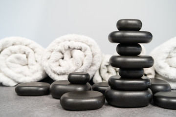 Obraz na płótnie Canvas stack of black basalt stones for massage on a white background in front of clean towels balance spa treatment concept