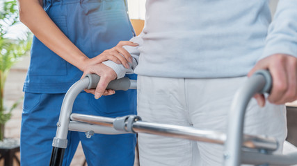 Cropped image of nurse helping senior woman to walk with walker at home - obrazy, fototapety, plakaty