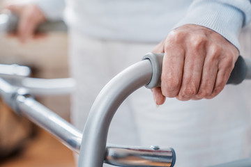 Close up image of elderly woman hands on walker. Elderly assistance concept