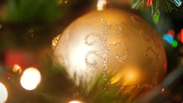 Macro 4k footage of golden bauble ball on christmas tree with glowing LED lights