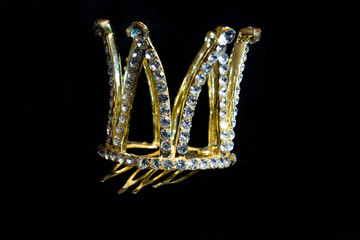 Gold crown with rhinestones for hair on a black background