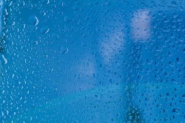 Raindrops on the surface of window panes Natural pattern of raindrops, on a blue background.