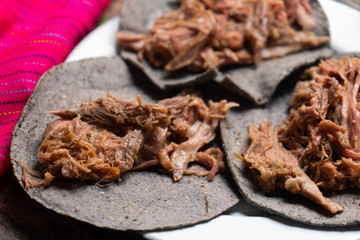 Mexican slow cooked lamb tacos also called barbacoa on wooden background