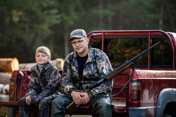 Hunter with his son during the rest sitting inside the pickup truck © romankosolapov