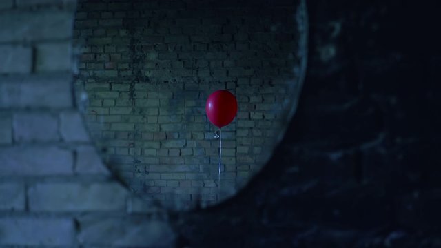 Mirror reflection of single red balloon appearing in strange abandoned place