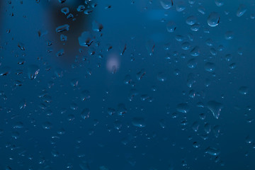 Raindrops on the surface of window panes Natural pattern of raindrops, on a blue background.