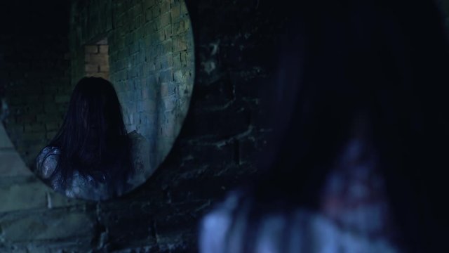 Scary faceless woman making creepy moves near mirror, portal to underworld