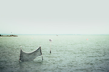 Caution sign and water volleyball court in the Lake Balaton. Minimalistic photo of a warning sign, water depth 120 cm and a net for background. Balaton is a famous tourist destination in Hungary. - Powered by Adobe