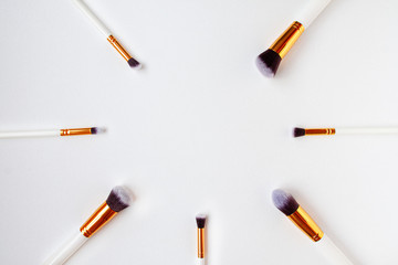 Fototapeta na wymiar Flat lay top view of female cosmetics brushes set for makeup on white background. Cosmetics and beauty concept with space for text in the middle.