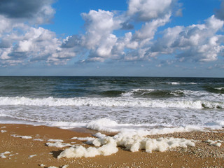 Stormy day on sea coast with beautiful blue sky with clouds and white waves nature background