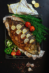 Baked fish river carp with aromatic herbs, spices, salt, vegetables, lemon, garlic, top view,...