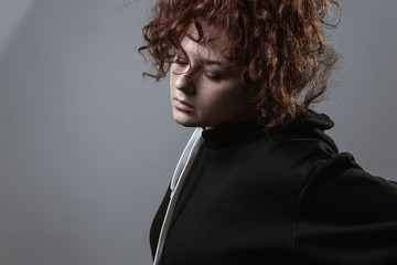 Portrait of a beautiful curly-haired girl with redheads on a gray background