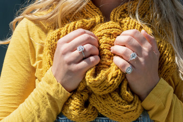 Closeup of oung woman wearing gold colored knitted scarf and diamond rings