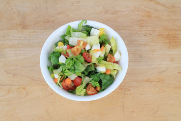 Dinner Salad ingredients in white bowl on old wooden cutting board.