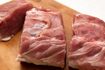 raw chopped pork steak on wooden cutting board