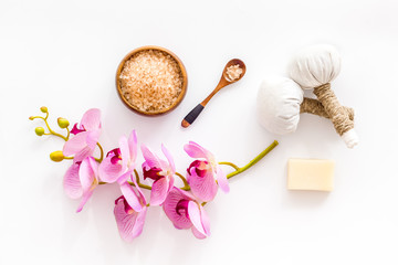 Massage table with thai herbal balls and orchids on white background top view pattern