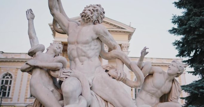Old sculpture Laocoon and his sons outdoors on city street. Translation from Russian: Odessa Archaeological Museum. Classic Rhodes monument and historical   building architecture with columns.