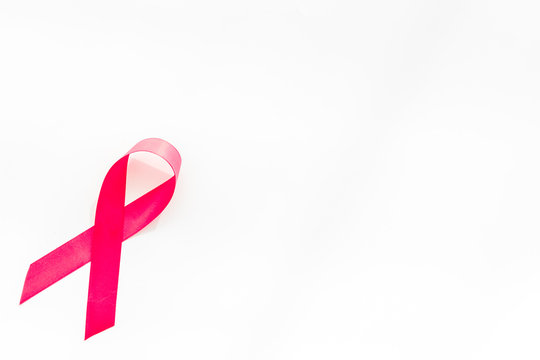 Pink ribbon as symbol of breast cancer awareness on white background top view copy space