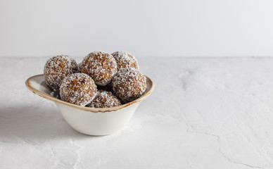 Homemade energy balls with dried apricots, raisins, walnuts, almonds and coconut. Healthy sweet food. Copy space. Energy balls in a bowl on a white background