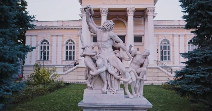 Old sculpture Laocoon and his sons outdoors on city street. Translation from Russian: Odessa Archaeological Museum. Classic Rhodes monument and historical   building architecture with columns.