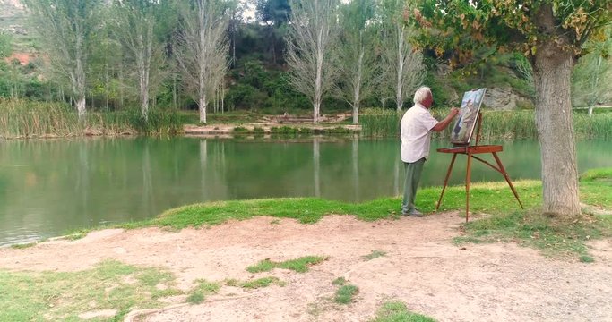 pintor senior en el bosque junto al río
