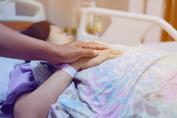 Close up focus on the Shake hands of a patient sick encourage encouragement on the bed in hospital ward.