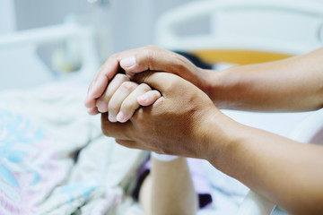 Close up focus on the Shake hands of a patient sick encourage encouragement on the bed in hospital ward.