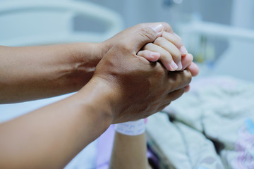 Close up focus on the Shake hands of a patient sick encourage encouragement on the bed in hospital ward.