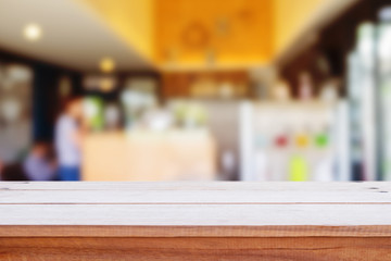 wooden table in front of abstract blurred  coffee shop.