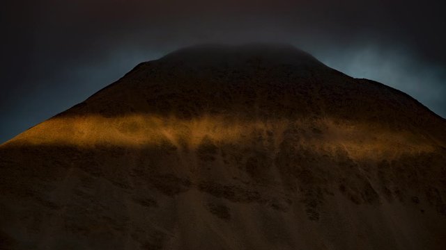Band of light accross barren mountain dark storm clouds Iceland abstract.mov
