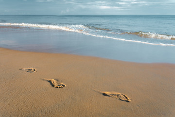 Texture sand and footprints near the water on the beach.The waves breaking the footprints on the beach.