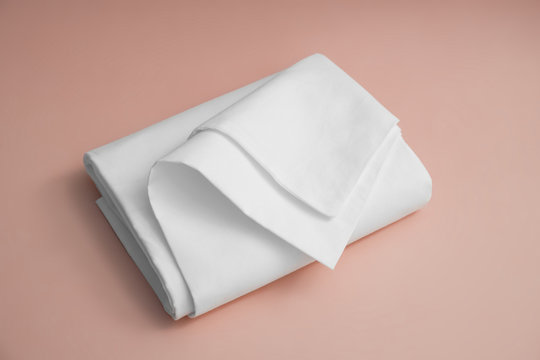 White bedding item against pink backdrop, folded white cotton sheet on a colored background for advertising, commercial and mock up