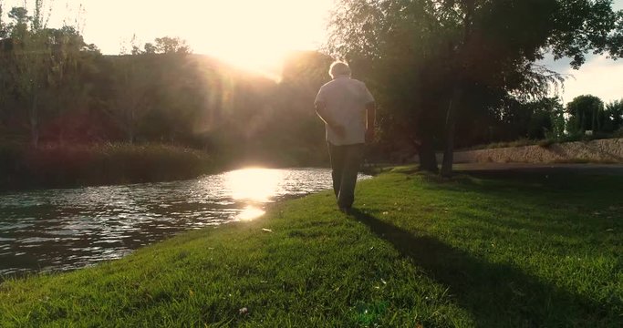 anciano dando un paseo campestre junto a r&iacute;o