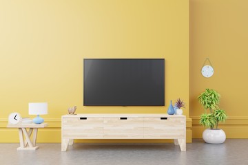 TV on cabinet in modern living room with lamp,table,flower and plant on yellow wall background.