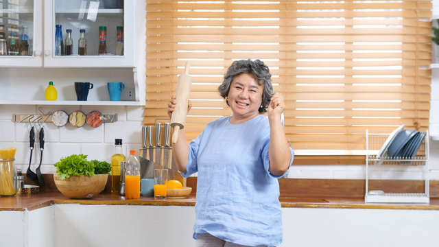 Happy senior woman dancing in kitchen, Elderly retirement female with happiness expression in lifestyle