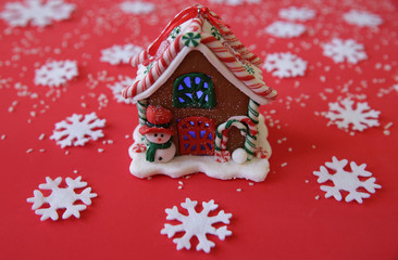 Christmas gingerbread house with a snowman on a red background with snowflakes. Close-up.