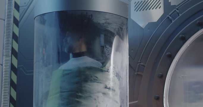 Male astronaut sleeping in a glass pod