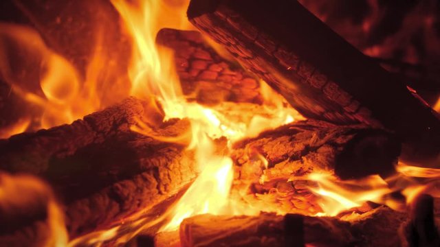 Closeup 4k video of burning wooden logs and flames in the fireplace