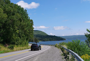 Car driving on a scenic highway beside a lake