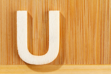 Letter U of wood-made alphabet, top view and space for text