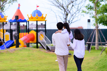 Naklejka premium warm family takes kid child to the park playground