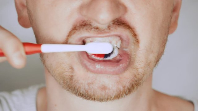 details lower face blond male brushing her teeth