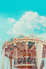 Retro pastel colorful Children's merry-go-round at the amusement park in the blue sky  and fluffy cloud background like in the heaven. © iareCottonStudio