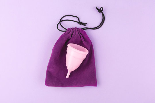 Menstrual cup and elegant bag on pink background.