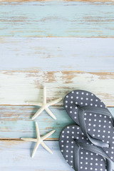 Cute grey polkadot slippers  with star fish grunge wooden background feel like summer season and traveling to the beach.